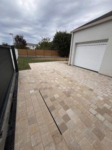 Allée de garage pavée devant une maison avec porte de garage blanche