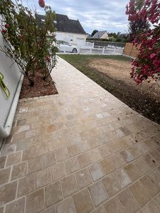 Allée de pavés en pierre naturelle devant une maison avec roses.