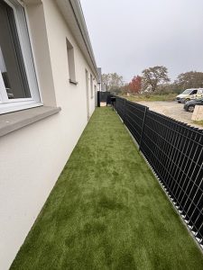 Allée latérale de maison avec pelouse synthétique et clôture noire