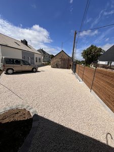 Allée de gravier devant une maison avec une voiture et une clôture en bois