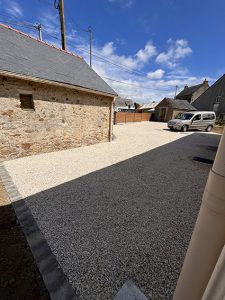 Gravel driveway leading to a stone building and a parked car