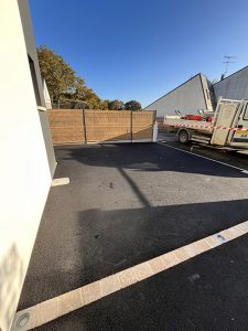 Allée pavée devant une clôture en bois et une maison moderne